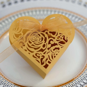 Detailed top view of golden heart-shaped favor box with laser-cut rose and ribbon
