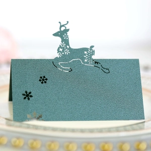 Detailed laser-cut dark green card with snowflake and reindeer patterns for table seating