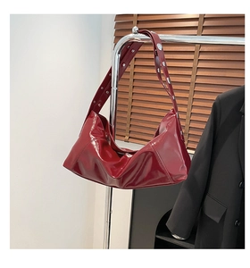 Detail of dark red glossy leather shoulder bag with silver rivet studs on the strap