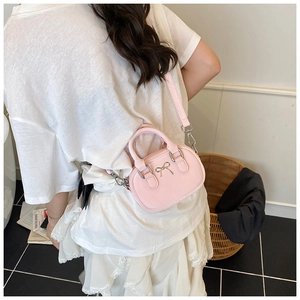 Mini light pink crossbody bag with metal bow detail worn by model in casual home setting