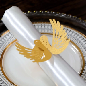 Macro shot of gold laser-cut swan wing napkin ring on white satin fabric