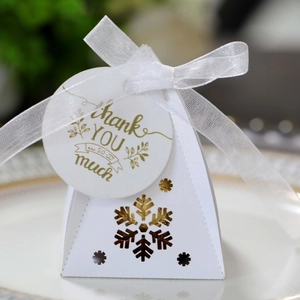 Detail van witte piramide geschenkdoos met gouden sneeuwvlok en zijden strik