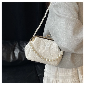 Detail of vintage beige kiss-lock bag with butterfly embroidery and pearl strap