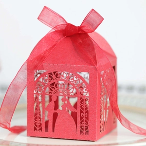 Detail of red hollow laser-cut wedding candy box with ribbon and bride groom silhouette