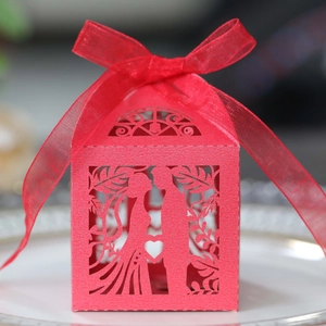 Detail of red laser-cut wedding favor box with romantic heart and ribbon on a plate