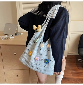 Dettaglio di una borsa tote in maglia azzurra con fiori colorati lavorati a mano in 3D
