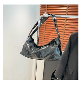 Detail of glossy black oil wax leather crescent bag with silver eyelet shoulder strap