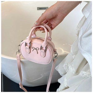 Detailed close-up of pink mini bowling bag with metal bow and smooth PU leather texture
