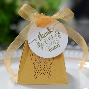 Detail of laser-cut hollow butterfly candy box with gold ribbon and thank you tag
