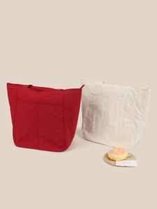 Dettaglio di borse tote in nylon rosso e beige con trama a pieghe e grandi tasche esterne
