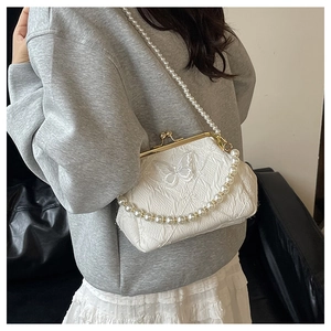 Detail of white kiss-lock handbag featuring butterfly embroidery and pearl strap chains