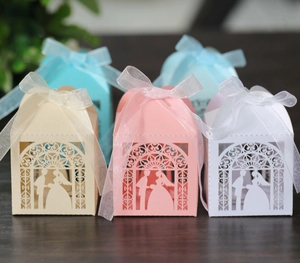 Detail of laser-cut wedding candy boxes with ribbon bows in multiple soft colors