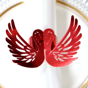 Detail of red hollow swan napkin ring with laser-cut wings on a white textile