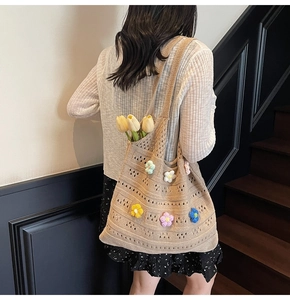 Dettaglio di borsa tote in maglia beige con motivi floreali 3D colorati all'uncinetto