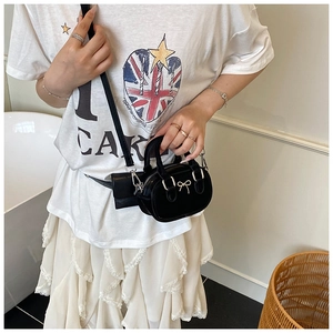 Mini black leather bowling bag with gold bow detail shown on a model for scale