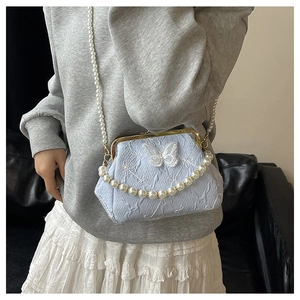 Detailed view of light blue embroidered handbag with butterfly appliques and pearl straps