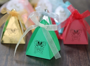 Macro shot of pyramid party gift boxes with laser-cut butterfly and ribbon bows