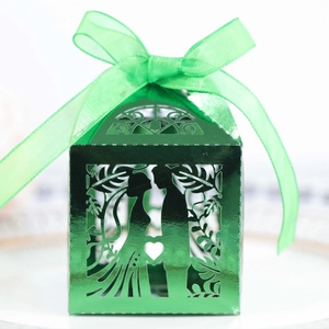 Detail of green laser-cut wedding favor box with ribbon and romantic silhouette