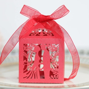 Detail of red laser-cut wedding candy box with couple silhouette and ribbon bow