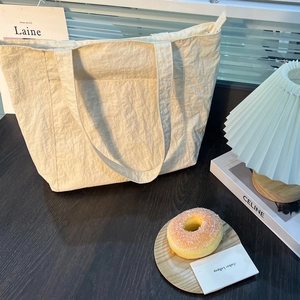 Dettaglio macro della borsa tote bianco crema con texture stropicciata e spalline larghe