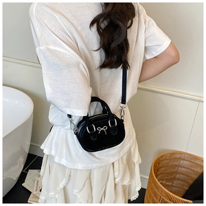 Mini black handbag with silver metal bow detail and dual handles shown with a model