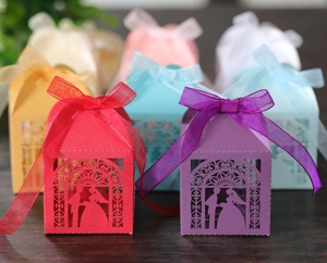 Detail of laser-cut wedding candy boxes with bride and groom silhouettes and silk ribbons