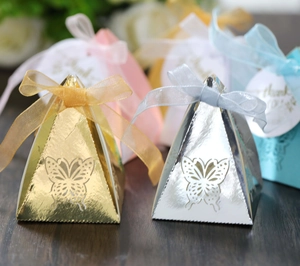 Macro shot of gold and silver pyramid candy boxes with hollow butterfly and ribbon bow