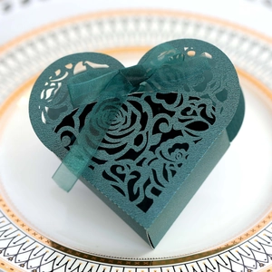 Detail of laser-cut rose patterns on dark green heart-shaped gift box with chiffon ribbon