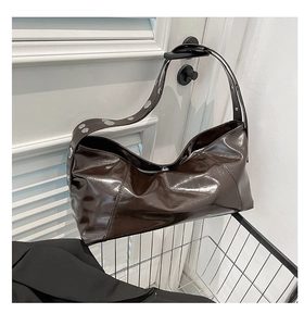 Detail of dark brown polished oil wax leather shoulder bag with silver rivet strap