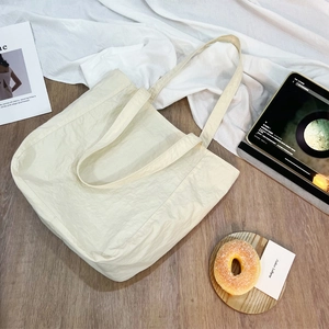Dettaglio della borsa tote in nylon pieghettato bianco avorio su legno chiaro