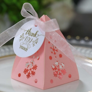 Macro-opname van roze piramide kerstsnoepdoos met holle sneeuwvlok en organzalint