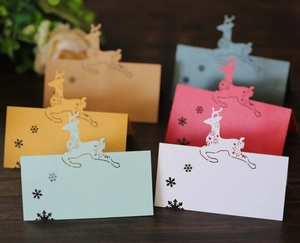 Detailed laser-cut Christmas reindeer and snowflake place cards on a wooden table