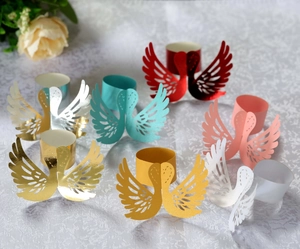 Close-up of laser-cut swan napkin rings in various shiny metallic and pearlescent colors