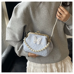 Close-up of light blue pleated bag with butterfly lace embroidery and gold clasp