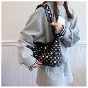 Détail du sac hobo en cuir noir avec des clous argentés et des œillets sur le mannequin