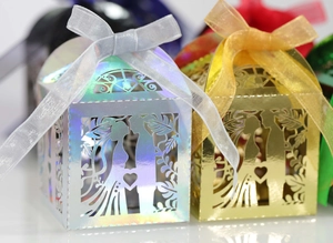 Macro detail of laser-cut wedding favor boxes with elegant ribbons and metallic finish