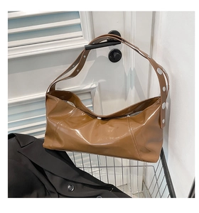 Detail showing glossy brown leather bag texture with silver metal buckle on white handle