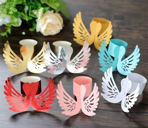 Detailed laser-cut swan napkin rings in seven diverse colors on dark wood table