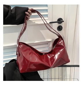 Detail of burgundy patent leather hobo bag featuring silver metal buckle on the strap