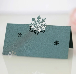 Close-up of laser-cut dark green snowflake place card with pearlescent paper texture