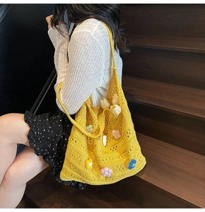 Dettaglio dei fiori colorati all'uncinetto e della trama a maglia della borsa gialla