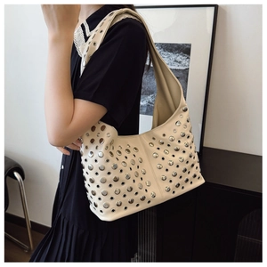 Détail du sac seau punk blanc cassé avec clous argentés et œillets sur la bandoulière