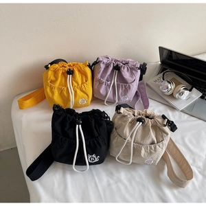 Detail of colorful nylon bucket bags with cat embroidery and wide shoulder straps