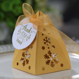 Macro detail van gouden piramide snoepdoos met sneeuwvlok uitsnede en gouden strik