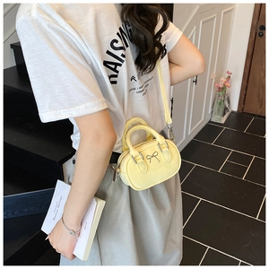 Close-up of yellow mini crossbody bag featuring a silver bow buckle and smooth leather finish
