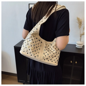 Détail d'un sac seau beige style punk avec rivets métalliques et œillets argentés polis