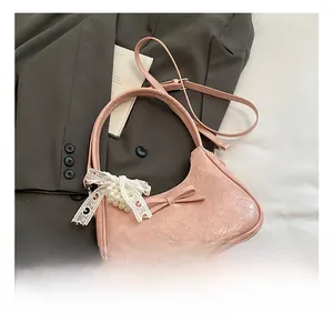 Dettaglio borsa a spalla rosa plissettata con fiocco e ciondolo di perle su un blazer