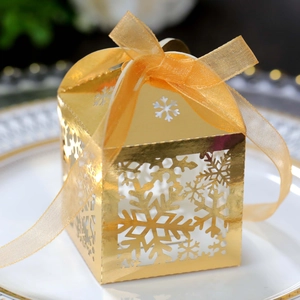 Macro shot of gold laser-cut snowflake candy box with organza ribbon on white plate