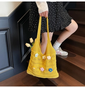 Dettaglio della borsa in maglia gialla con fiori all'uncinetto 3D e texture traforata