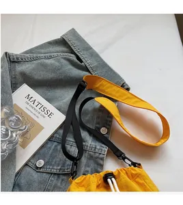Detail of yellow canvas bucket bag with adjustable black strap and soft shoulder pad